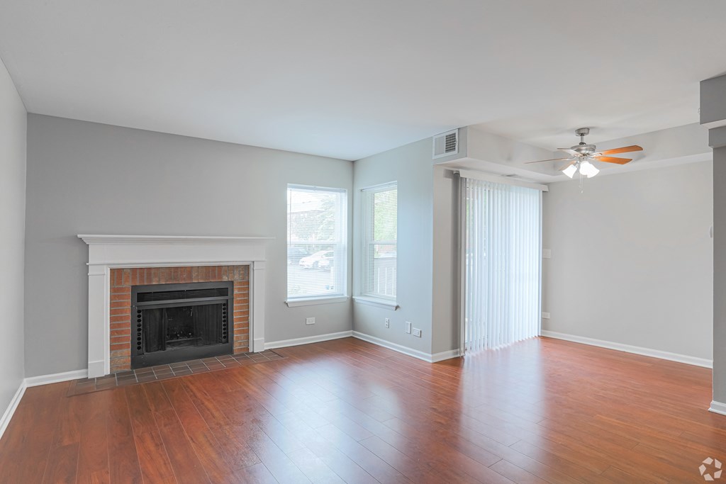 an empty living room with a fireplace and a ceiling fan