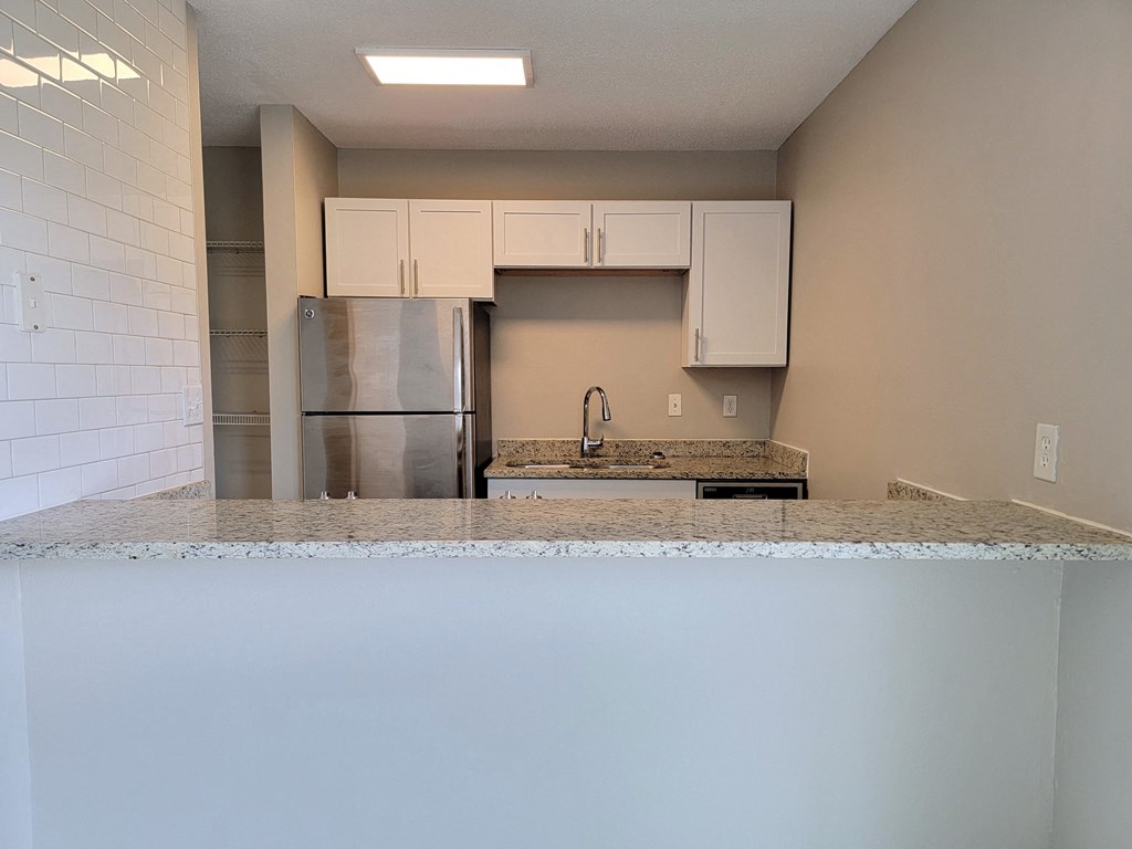 an empty kitchen with a granite counter top and a stainless steel refrigerator
