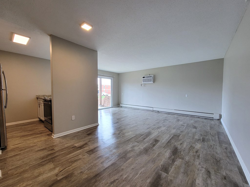 the living room and dining room of an apartment with wood flooring