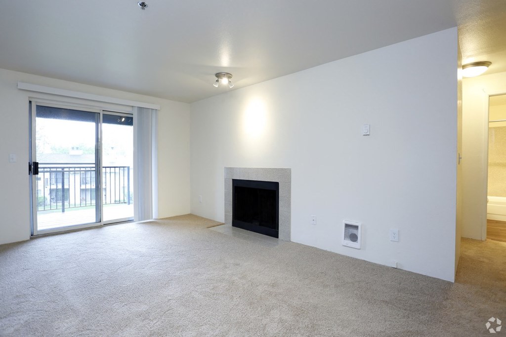 an empty living room with a fireplace and a balcony