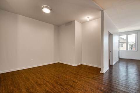 an empty living room with wood floors and white walls