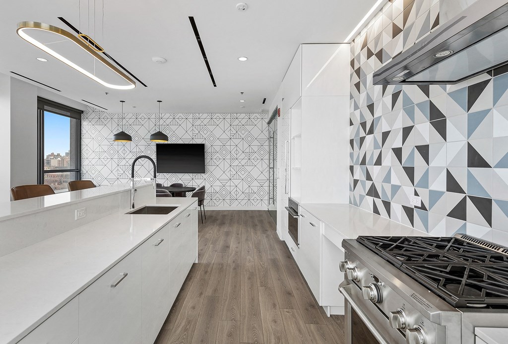a kitchen with white counters and a stove and geometric tiles on the wall
