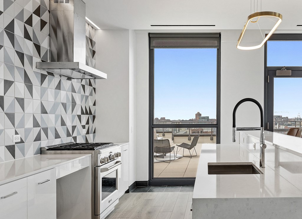 a kitchen with white countertops and a door to a balcony