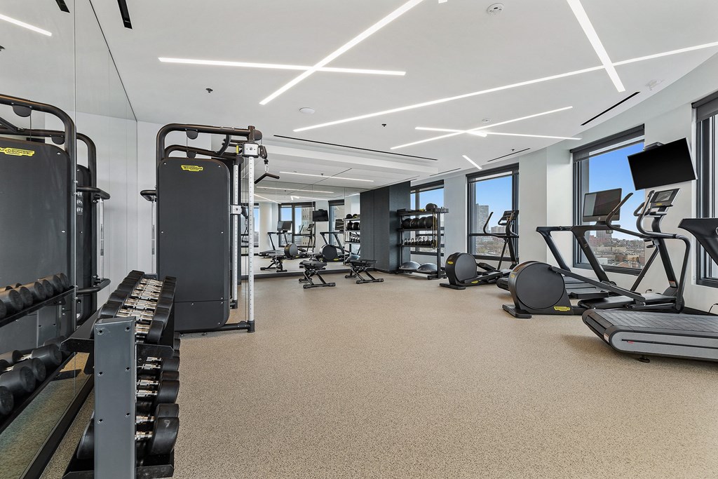 A spacious gym with various exercise equipment and a large mirror on the wall.