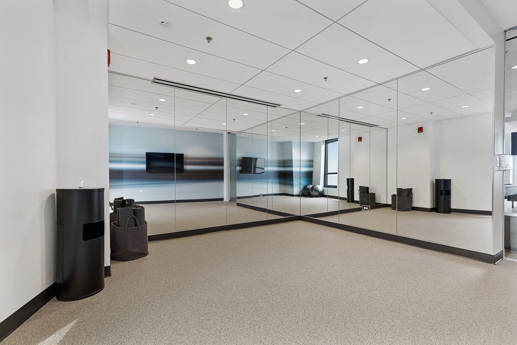 A hallway with a glass wall and a trash can.