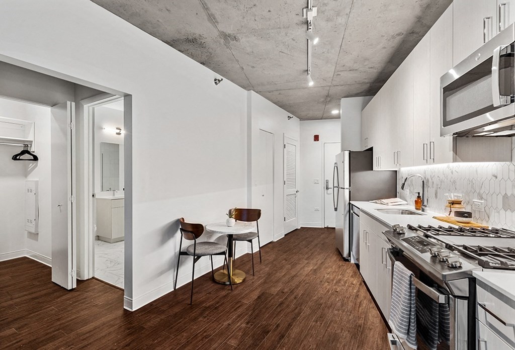 a kitchen with white cabinets and a stove top oven and a table with a chair