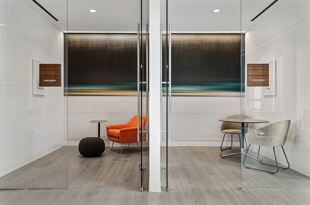 a meeting room with glass walls and a orange chair and a table