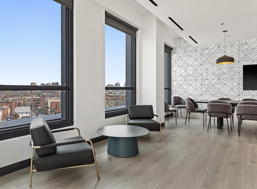 a lounge area with chairs and tables and a window with a city view