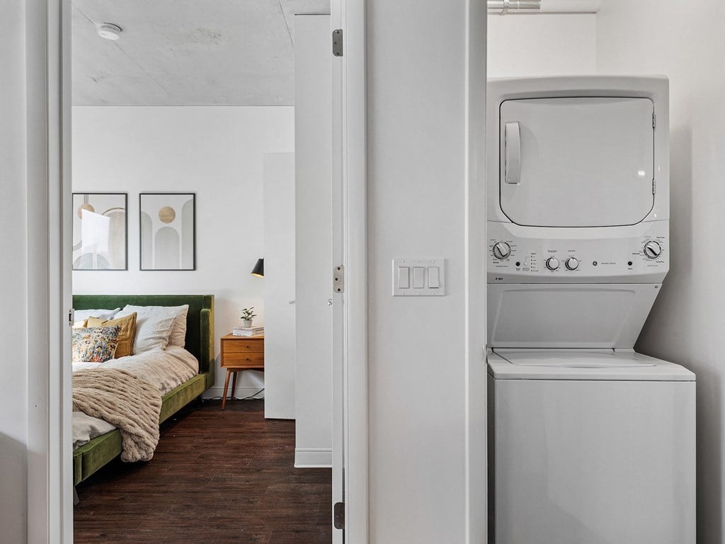 a room with a bed and a washer and dryer in it