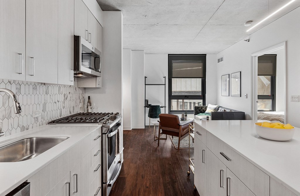 a kitchen and living room with white cabinets and a sink