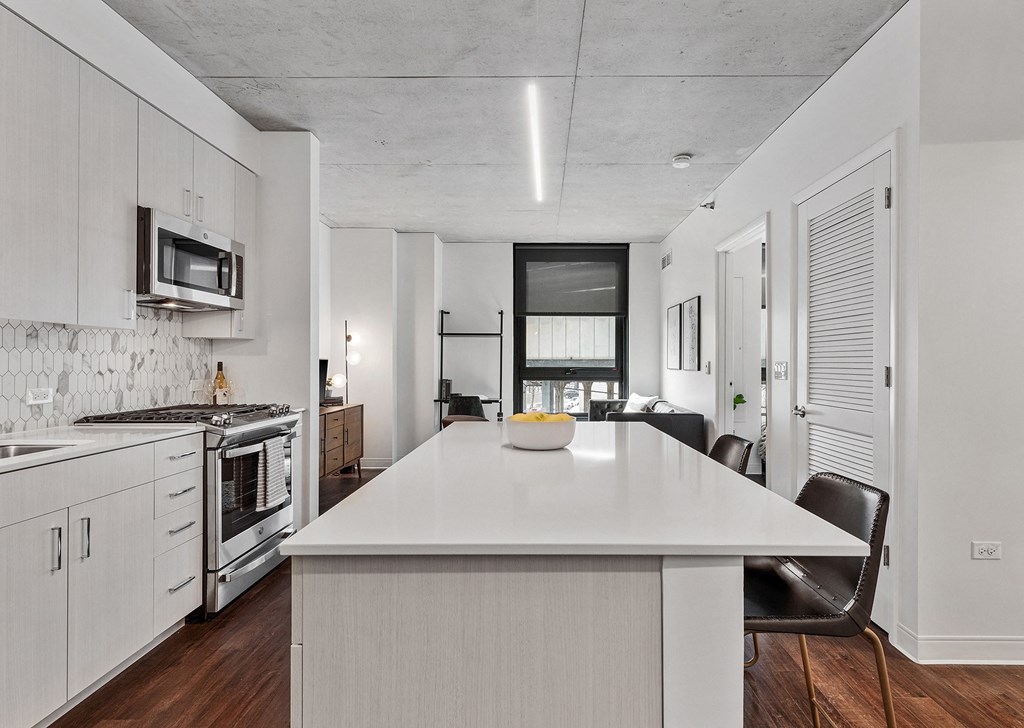 an open kitchen with a large white island and a dining table