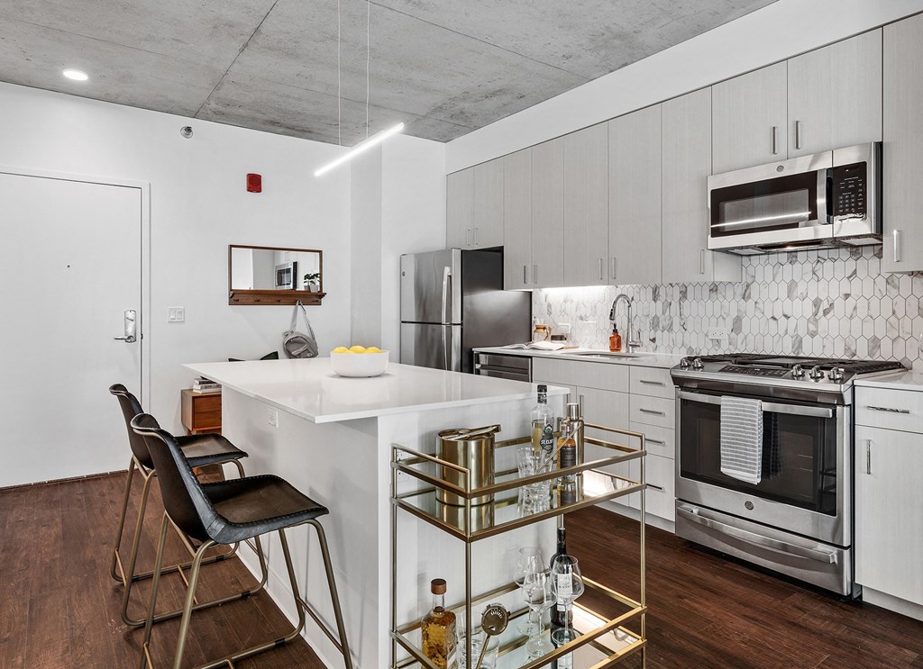 a white kitchen with a white island and stainless steel appliances