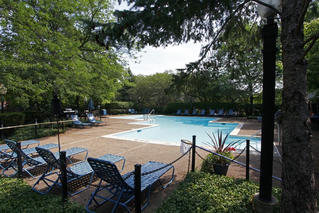 a swimming pool with tables and chairs next to it