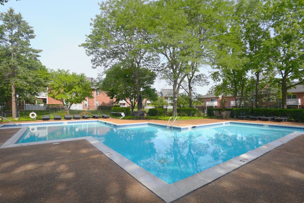 a large pool with trees and a building in the background