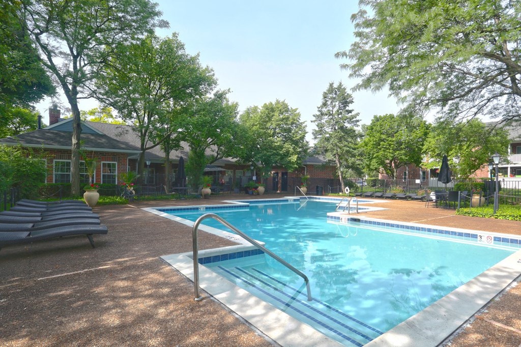 a swimming pool in front of a building with trees