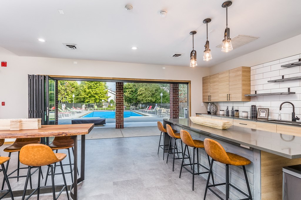 a kitchen with a bar and stools in front of a pool