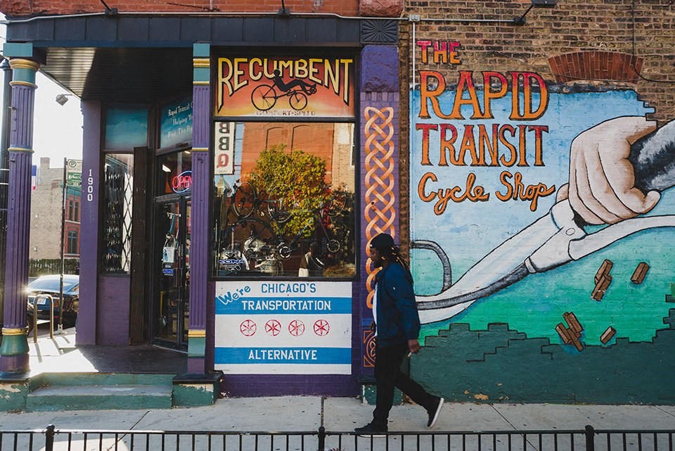 a woman walking down the sidewalk in front of a building with a mural