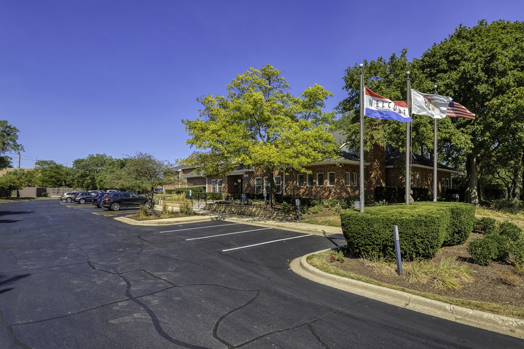 a parking lot with flags in front of a building with cars parked