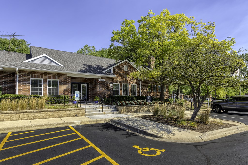 a brick building with a parking lot and a tree in front of it
