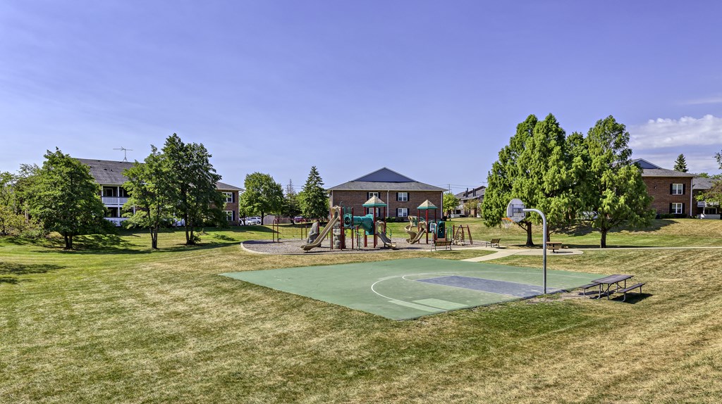 a basketball court in a park with houses in the background