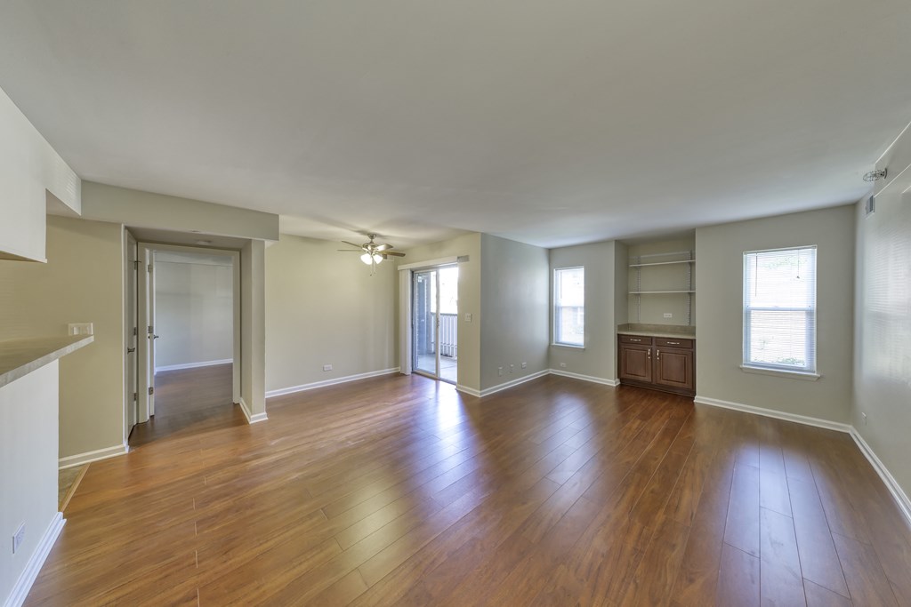 an empty living room with hard wood flooring and a window