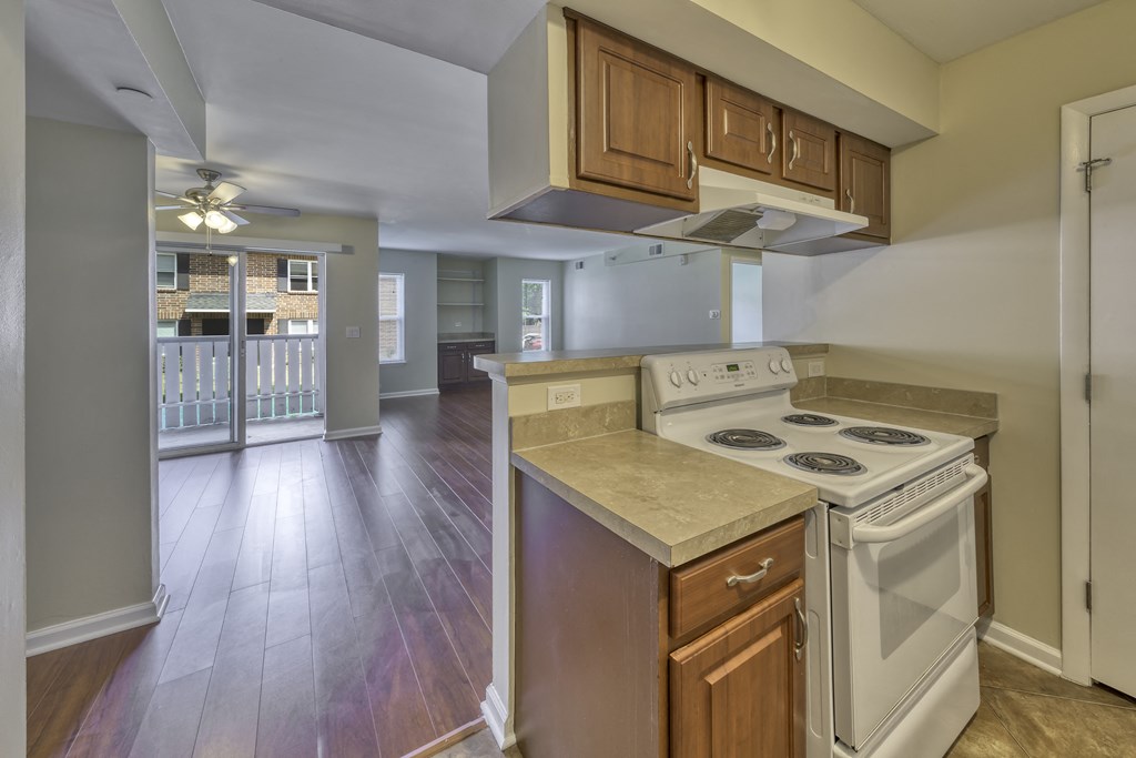 an empty kitchen with white appliances and wood floors