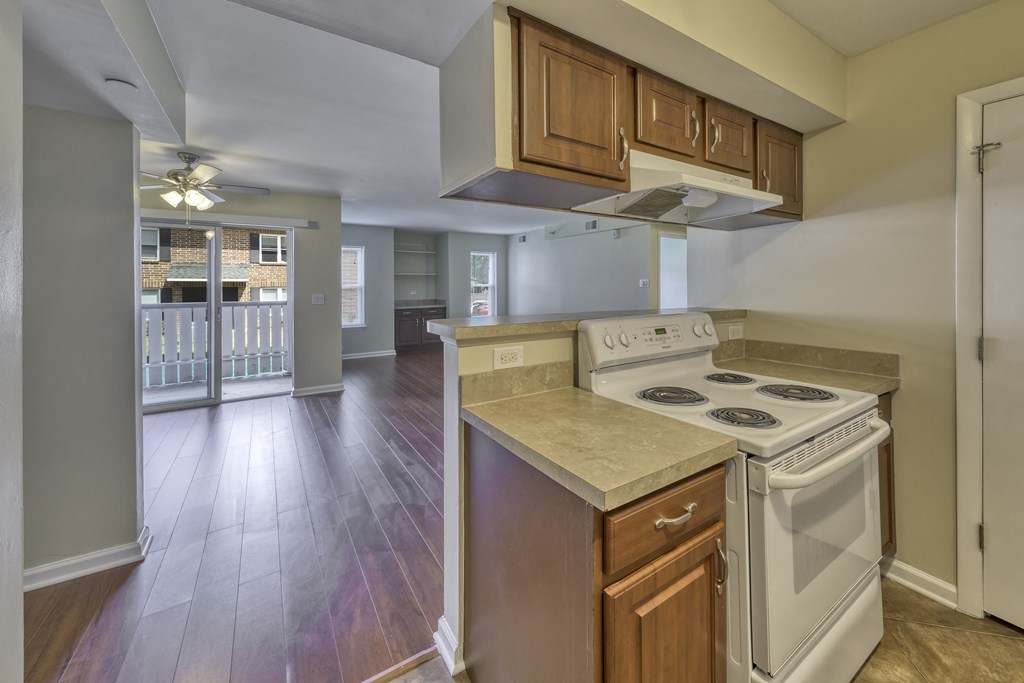 an empty kitchen with white appliances and wood floors