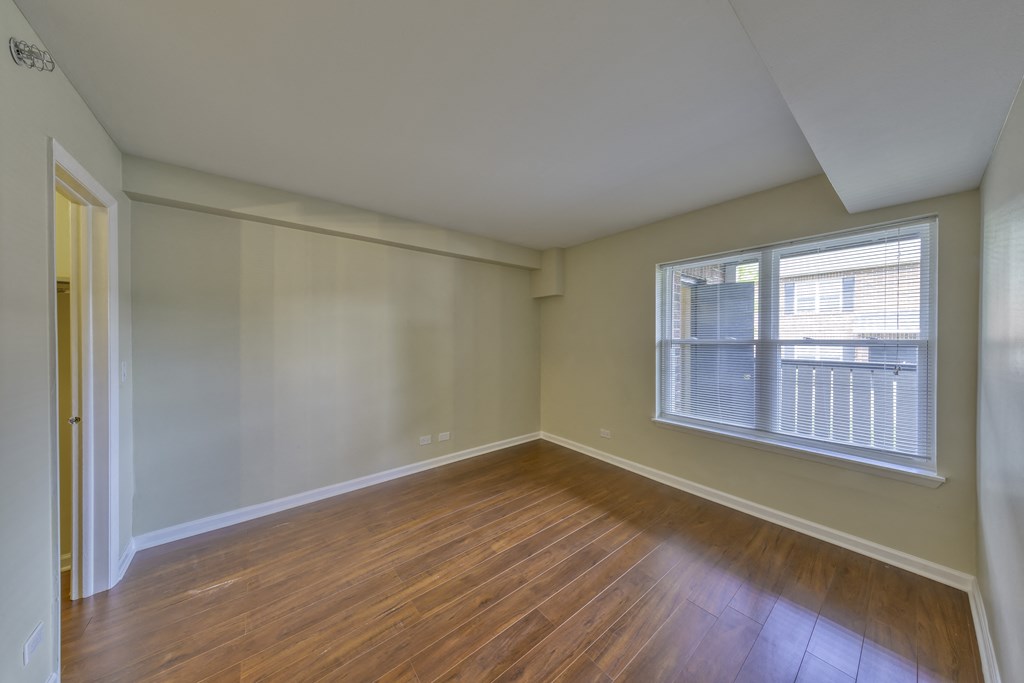 an empty living room with wood floors and a large window