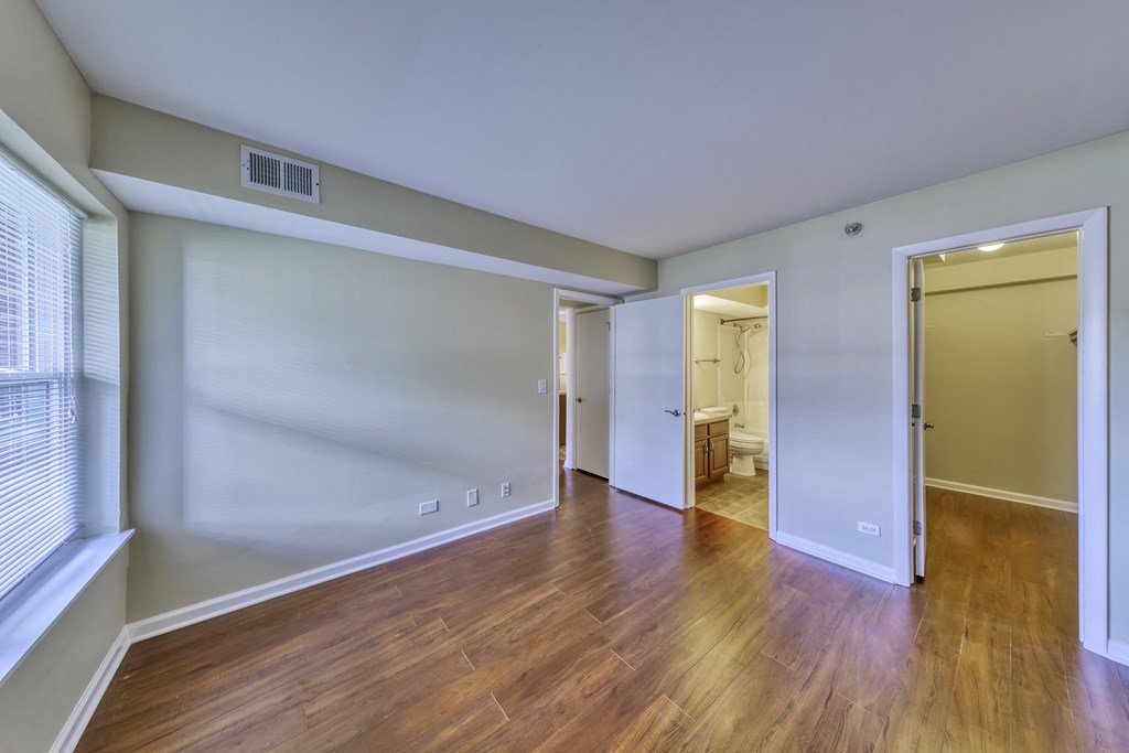 an empty living room with wood flooring and a door to a bathroom