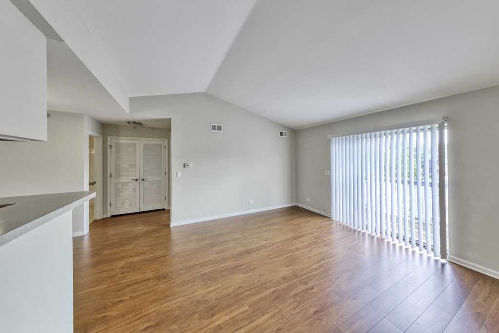 an empty living room with wood flooring and a large window