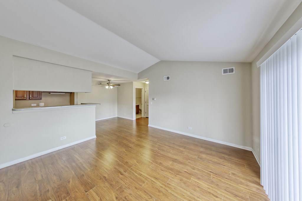 the living room and kitchen of an empty apartment with wood flooring