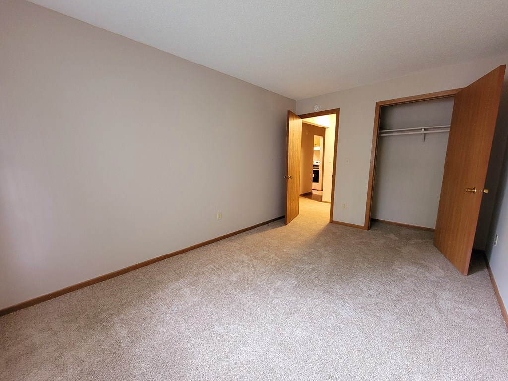 an empty bedroom with a closet and a door to a bathroom