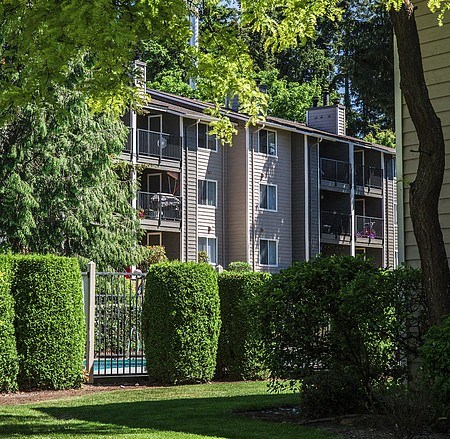 an apartment building with balconies and manicured bushes