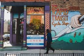 a man walking down a sidewalk in front of a building with a mural