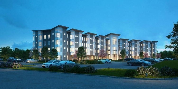 an image of an apartment building at dusk with cars parked in a parking lot