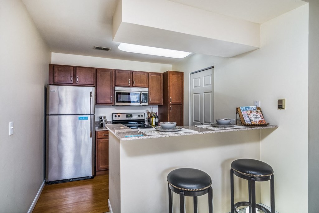 a kitchen with stainless steel appliances and a bar with three stools