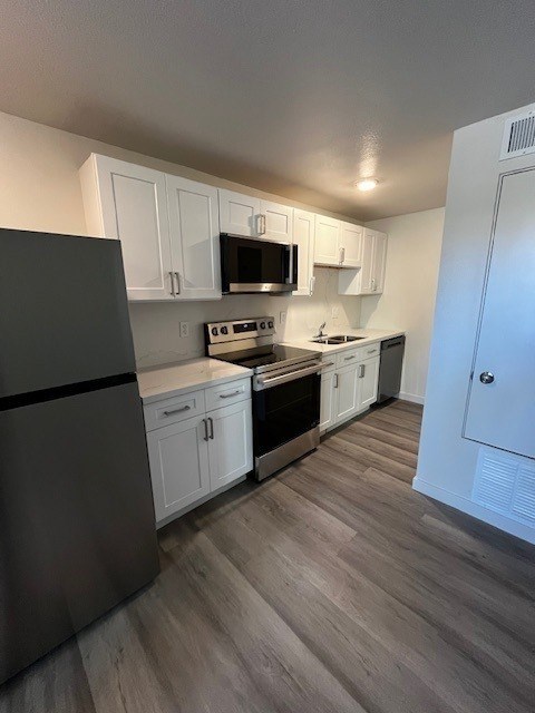 A kitchen with a black refrigerator and white cabinets.