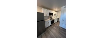 A kitchen with a black refrigerator and white cabinets.