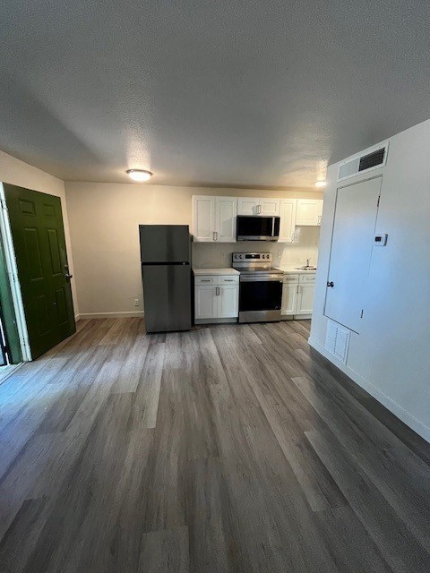 A kitchen with a black fridge and white cabinets.