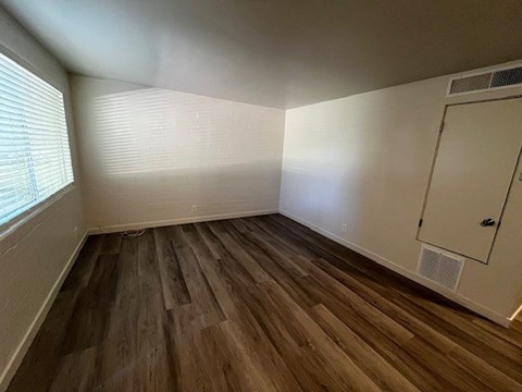 A room with wooden flooring and a window with blinds.