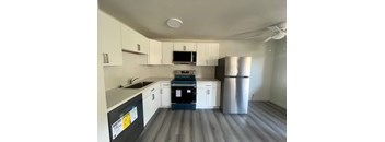 A kitchen with white cabinets and a black fridge.