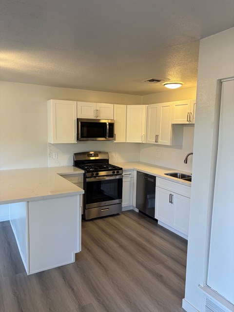 A kitchen with white cabinets and a stove top oven.