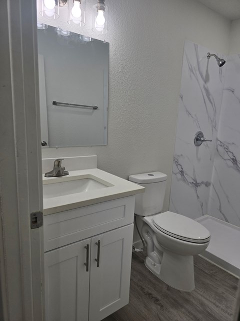 A white bathroom with a marble shower.