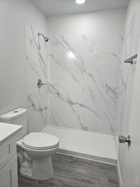 A white toilet in a bathroom with marble wallpaper.