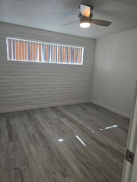 A room with a ceiling fan and a window with blinds.