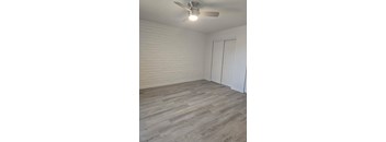 A room with a ceiling fan and a wooden floor.