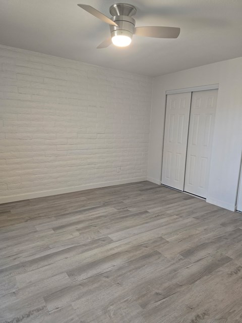 A room with a ceiling fan and a wooden floor.