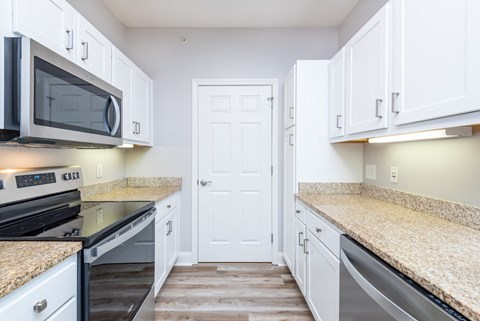 a kitchen with white cabinets and granite counter tops