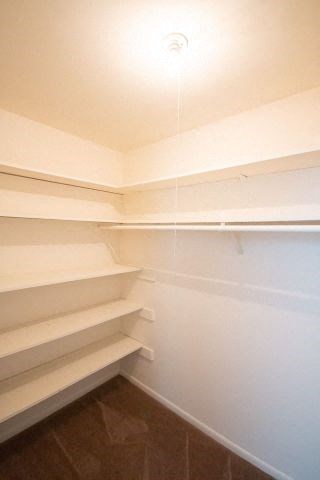 a white walk in closet with empty shelves