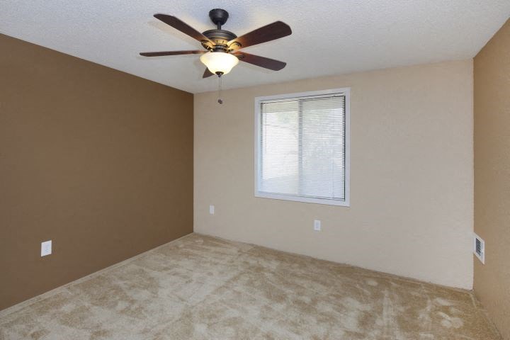 an empty room with a ceiling fan and a window